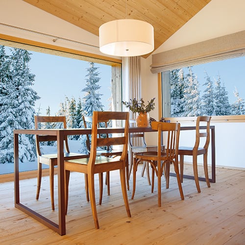 Gemütlicher Essbereich aus Holz. Aussen herrscht Winter. Innen ist es angenehm warm.