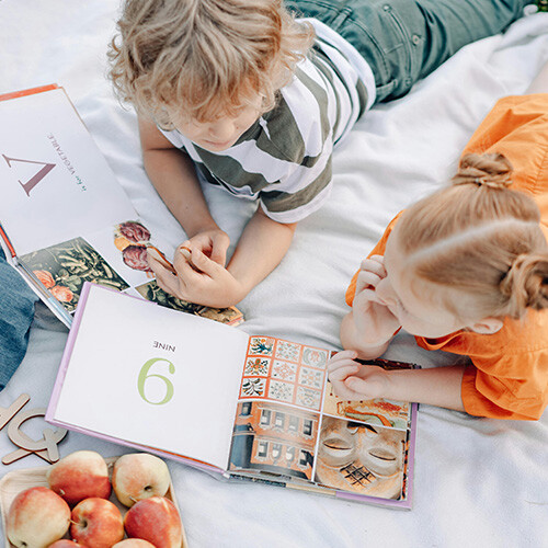 Due bambini si godono l'estate su una coperta da picnic in un giardino con le nuove finestre EgoKiefer